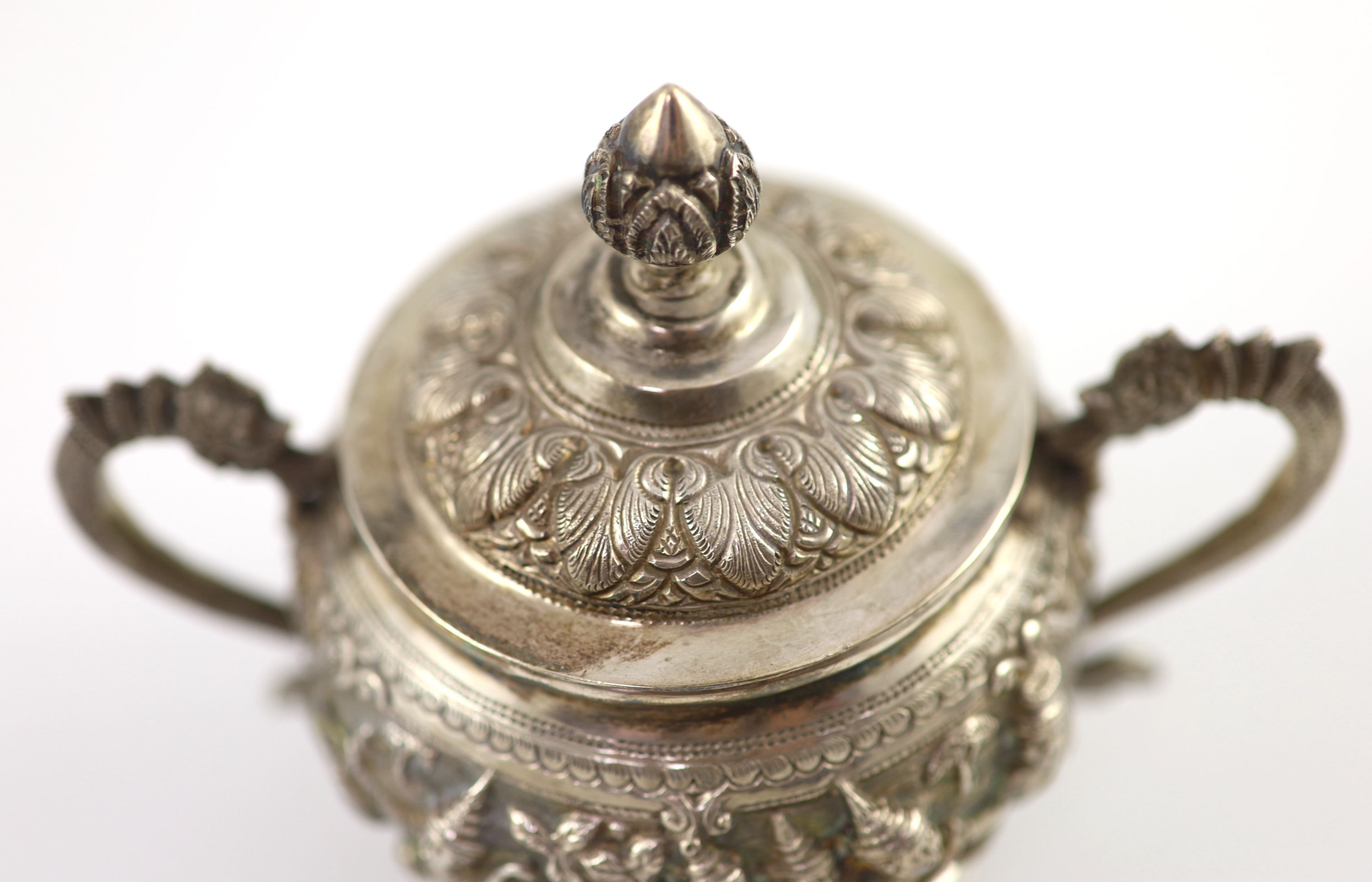 An impressive Burmese Sterling silver (950) three-piece tea service, with tray, cast with figures, teapot with cockerel spout and figural handle